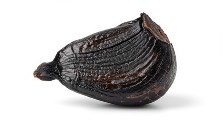 Obraz premium Single black garlic clove isolated on white background, fermented food with health benefits