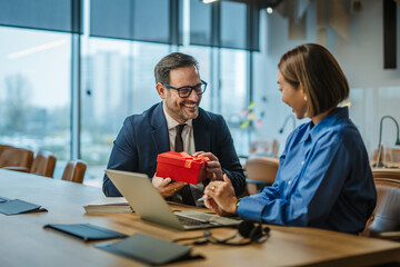 Businessman giving a red gift box to a colleague