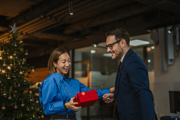 Business colleagues exchanging christmas gift during office holiday celebration