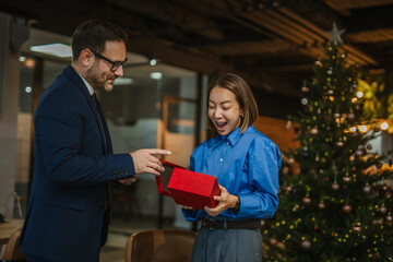 Colleagues exchanging christmas gift during office holiday celebration
