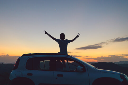 Brazilian traveler enjoying a sunset road trip moment, arms raised in freedom and joy. Authentic wellness vibe, outdoor lifestyle, mindful travel and positive energy for modern adventure seekers