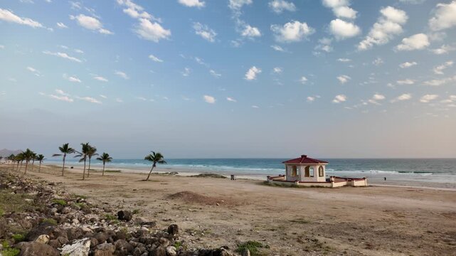Mughsayl Beach close to Salalah, Dhofar, Oman, showcases a beautiful coastal landscape with blue skies, calm sea, and distant mountains in dry season.
