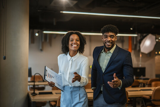 Smiling business professionals walking through modern office discussing work