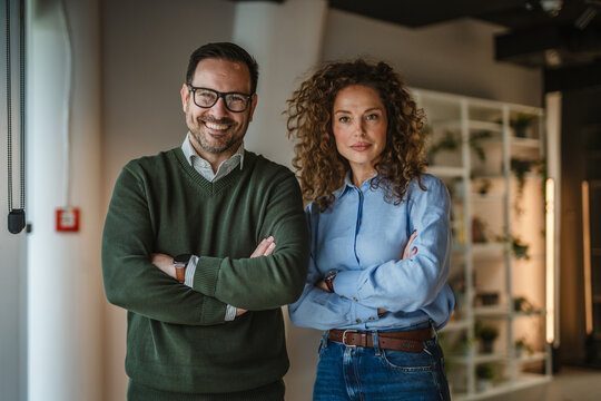 Business colleagues standing arms crossed in modern office