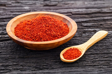 Ground or crushed organic annatto in the spoon and in the bowl - Bixa orellana