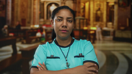 Referee woman in turquoise jersey with whistle stands with arms crossed in church interior with pews and arches; rejection.