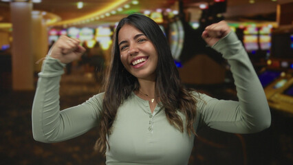 Woman celebrating inside a lively casino with slot machines, exuding joy and excitement, showcasing...