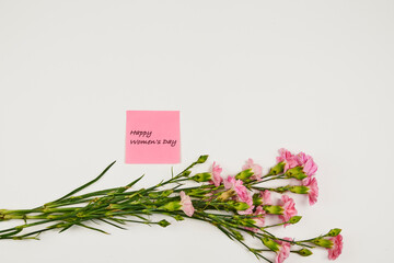Bouquet of pink carnations with a congratulatory tag for Women's Day, with copy space