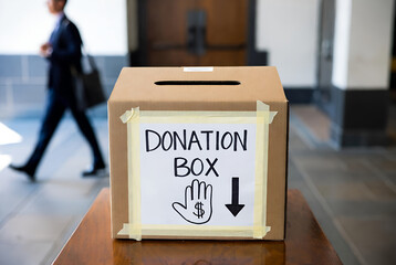 Donation box in public hallway for charity support with hand symbol and arrow guiding contributions
