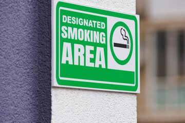Designated smoking area sign on wall. Clear green smoking area sign on a city wall, perfect for regulation, public space and urban lifestyle themes. © Denis