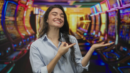 Woman finger pointing to open palm beside glowing slot machine reels in a vibrant casino;...