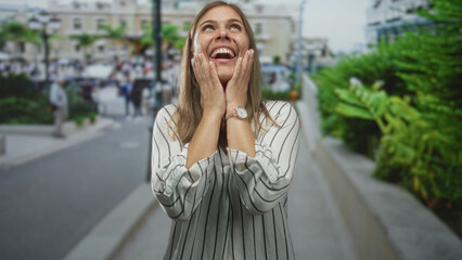 Fototapeta premium Woman raising open palms and shrugging shoulders on crowded daytime street; joy confidence optimism.