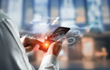 A businessman interacts with a smartphone displaying holographic graphs and charts, illustrating modern data analysis and financial management in a tech-driven office setup. Scalp