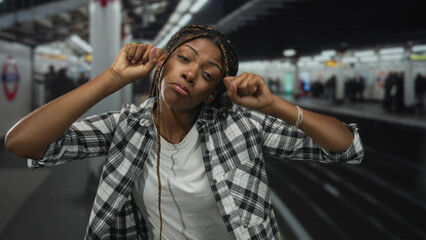 Woman with fists by her face inside a train station building, arms raised in a mock boxing gesture; playful confidence.