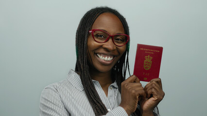 Woman smiling while holding a danish passport against a white background, wearing red glasses and striped shirt; she exudes confidence and joy.