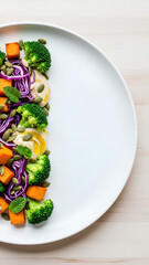 Top view of a plate with colorful plant-based food arranged on the left half, right half of the plate and surrounding table kept mostly empty as negative space, fresh and healthy look.