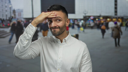 Young hispanic man on urban street outdoors looking thoughtful with hand on forehead as diverse...
