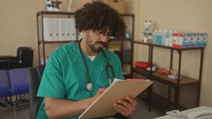 Man doctor with stethoscope writing on clipboard in clinic building, seated at desk and checking notes; focused care.