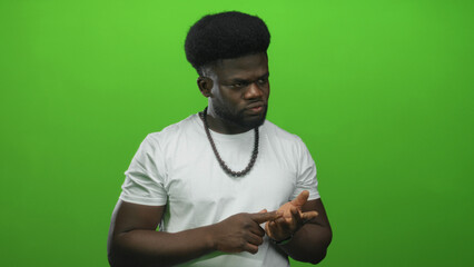 Man in white t shirt points finger to palm while wearing beaded necklace in studio; concentration counting numbers.
