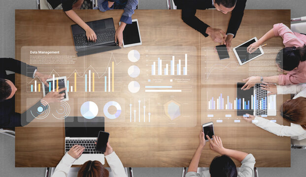 A top-down view of a business meeting featuring digital graphs and devices on a wooden table, showcasing teamwork and collaborative data management in a modern corporate setting. Gantry