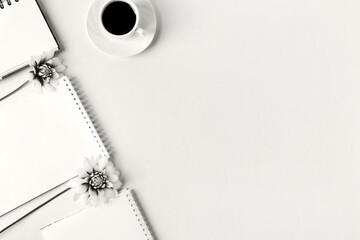 Demonstrating the colors of 2026 - Cloud Dancer. Opened blank notepad with flowers and a cup of coffee. Festive office desktop concept.