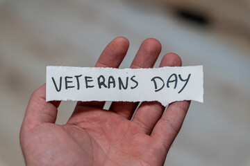 A hand holding a handwritten note that reads Veterans Day, symbolizing remembrance and appreciation for military service. This captures the essence of honoring veterans on this special occasion.