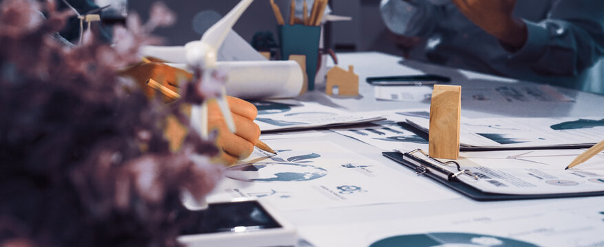 Professionals in a collaborative workspace focus on sustainable development projects. Green technology and eco-friendly materials enhance team brainstorming and productivity. SACTR - Powered by Adobe