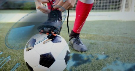Player pressing foot on ball, tying laces for kick in sports, blue overlay highlighting laces