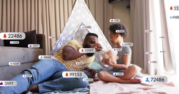 Father leaning in daughter giving teddy by teepee causing icons tracking social media while bonding