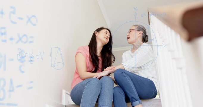 Daughter reaching for mom's hand on stairs, comforting mom, blue equations overlaying wall