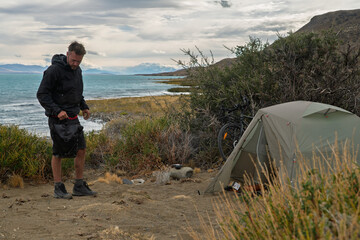 Hiker wild camping by turquoise Lago Argentino in Patagonia, Argentina