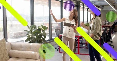 Tablet-holding woman guiding, VR-wearing woman reaching to test technology demo graphic overlays