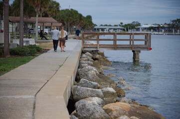 Scenic Marina Sidewalk View with people walking Background. St. Petersburg, FL Tranquil scene featuring a marina with several yachts docked, fishing dock and a serene waterfront setting perfect for re