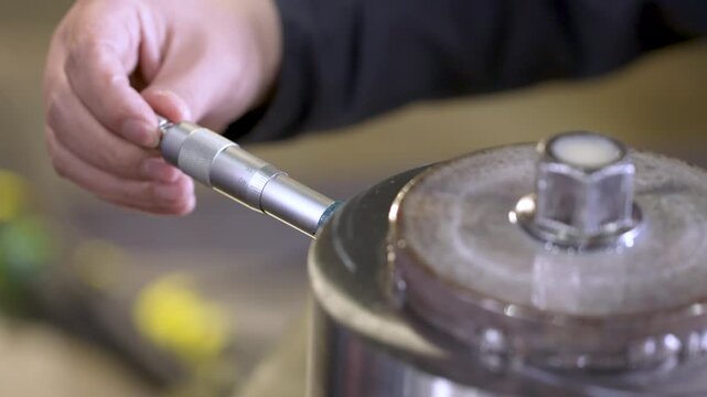 Industrial Worker Measuring Engine Part with Micrometer