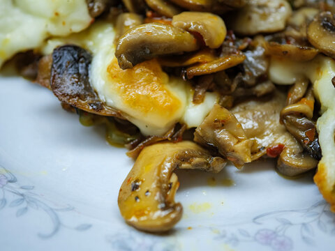 Detail of saut&eacute;ed cultured mushrooms and melted kashar cheese in a ceramic stew pot showing the juicy texture of the cooked vegetables and rich sauce
