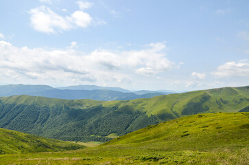 Obraz premium Breathtaking mountain landscape with rolling green hills and a deep valley under a cloudy sky. Perfect for nature, travel, and outdoor lifestyle scenes conveying calm, vastness, and natural beauty