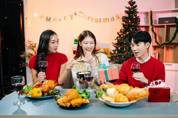 Asian friends capture the holiday spirit with gifts, laughter, and a festive Christmas dinner in a cozy, joy-filled setting