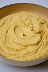 Top view of a bowl of smooth creamy hummus garnished with olive oil and spices representing a traditional middle eastern vegetarian dish