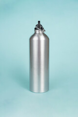 The silver water bottle stands out elegantly against the bright blue background