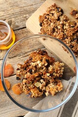 Tasty granola with honey, nuts and raisins on wooden table, flat lay