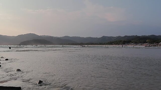 Coastal Landscape of Lombok Beach at Sunset with Crowds of People Enjoying the Shallow Water, Indonesia at Lombok, Indonesia - June 22, 2025