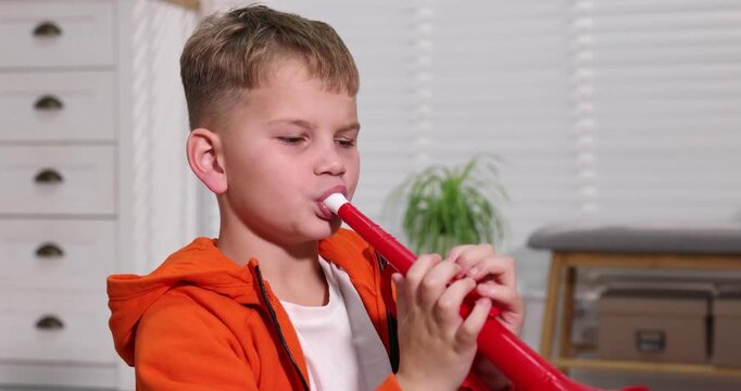Little boy playing toy trumpet at home