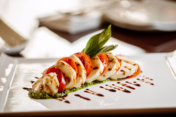 Caprese salad served on a white plate with a garnish at a high end Italian restaurant 