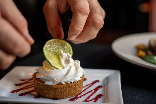 A chef places a lime slice onto a slice of key lime pie at a high end restaurant