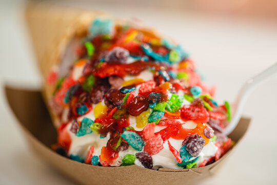 A vanilla ice cream cone topped with colorful fruity pebbles cereal
