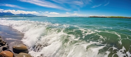 Beautiful coastal scenery with waves crashing on the shore under a bright blue sky.