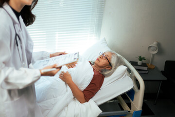 Doctor consulting elderly patient lying on hospital bed