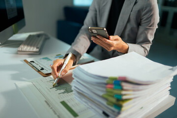 Businesswoman multitasking with smartphone analyzing financial data
