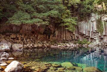 Cheonjeyeon Waterfall, A serene view of crystal-clear waters surrounded by lush greenery, capturing the essence of Jeju Islands natural wonders