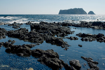 A panoramic view of the turquoise sea and distant islands from Jeju Island, highlighting the stunning coastal landscape